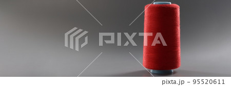 Red colour thread spool on grey background, yarn for sewing, bright thread for dressmaking Red colour thread spool on grey background, yarn for sewing, bright thread for dressmaking 95520611