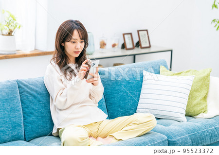 リビングでスマホを見る若い女性 95523372