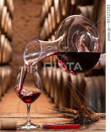 Winery. Pour red wine from the decanter into the wine glass for tasting. 95527203