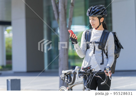 スマホを手に持ってロードバイクを引いているフードデリバリー 女性配達員 スマホを手に持ってロードバイクを引いているフードデリバリー 女性配達員 95528631