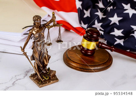 A statue justice with administration documents folders standing on lawyer's desk is depicted by the law A statue justice with administration documents folders standing on lawyer's desk is depicted by the law 95534548