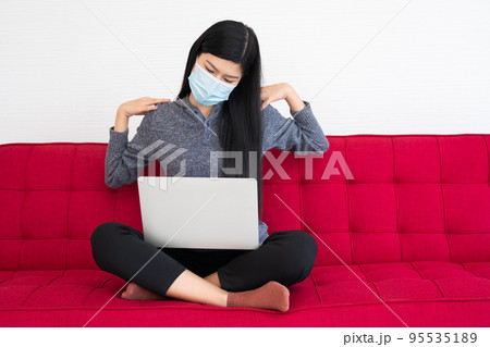 Tired woman wearing a face mask, pain in neck tensed muscles fatigued from computer work, suffering of office syndrome after long hours work on computer. Office syndrome and Health care concept. Tired woman wearing a face mask, pain in neck tensed muscles fatigued from computer work, suffering of office syndrome after long hours work on computer. Office syndrome and Health care concept. 95535189