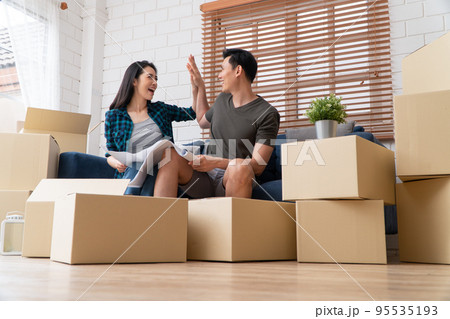 Smiling young Asian happy couple hold blueprint for home decoration ideas at moving day in their new home after buying real estate. Concept of starting a new life for a newly married couple. Smiling young Asian happy couple hold blueprint for home decoration ideas at moving day in their new home after buying real estate. Concept of starting a new life for a newly married couple. 95535193