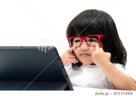 Little Asian Preschooler girl wearing red glasses and using tablet pc on white background, Asian girl talking and learning with a video call with a tablet, Educational concept for school kids. 95535468