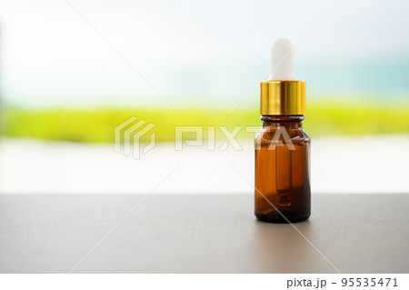 A brown glass bottle with dropper on the table. Concept of aroma oil, cosmetic, and beauty skin. 95535471