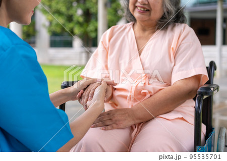 Asian careful caregiver or nurse hold the patient hand and encourage the patient in a wheelchair. Concept of happy retirement with care from a caregiver and Savings and senior health insurance. Asian careful caregiver or nurse hold the patient hand and encourage the patient in a wheelchair. Concept of happy retirement with care from a caregiver and Savings and senior health insurance. 95535701