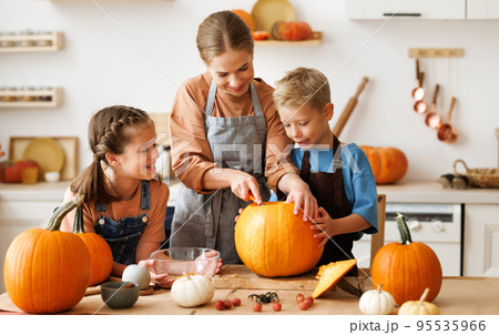 Children and mom making Jack-o-Lantern together at home, carving Halloween pumpkin 95535966
