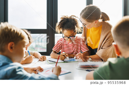 Teacher helping children with schoolwork at school Teacher helping children with schoolwork at school 95535968