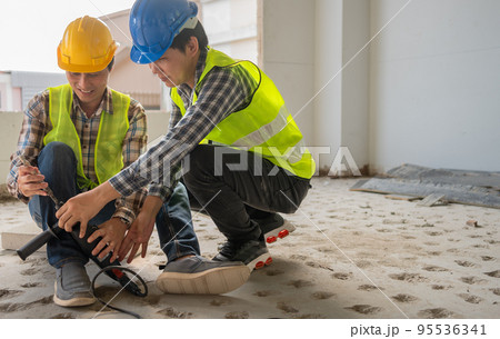 Engineer teaching worker for use electric jackhammer for perforator equipment making holes the floor to be strong at construction site, Concept of worker and residential building Engineer teaching worker for use electric jackhammer for perforator equipment making holes the floor to be strong at construction site, Concept of worker and residential building 95536341