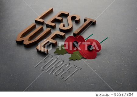World War remembrance day. Lest we forget words and red paper poppies on dark stone background World War remembrance day. Lest we forget words and red paper poppies on dark stone background 95537804