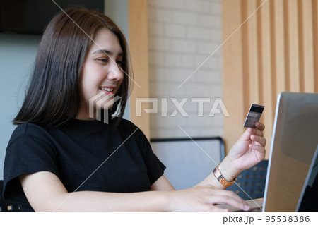 Online payment with Young Women hands holding credit card and using computer for online shopping. 95538386