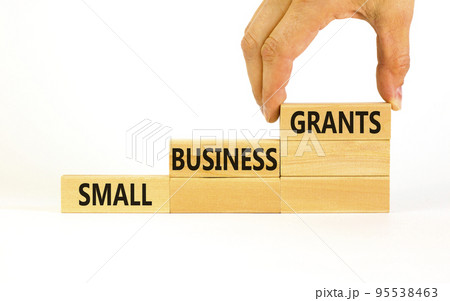 Small business grants symbol. Concept words Small business grants on wooden blocks on a beautiful white table white background. Businessman hand. Business, finacial and small business grants concept. Small business grants symbol. Concept words Small business grants on wooden blocks on a beautiful white table white background. Businessman hand. Business, finacial and small business grants concept. 95538463