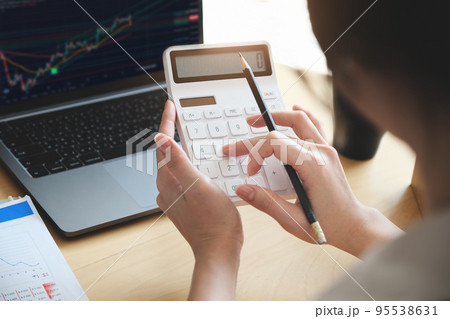 Business woman using calculator and computer to trade charts to find buy and sell points for her port. 95538631
