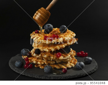 Fresh crispy Belgian waffles with fresh blueberries blackberries cranberries and red currants 95541048