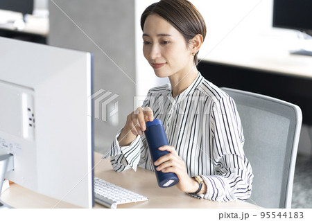 オフィスでマイボトルを使う女性 95544183