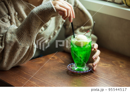 カフェでメロンソーダを飲む女性 95544517