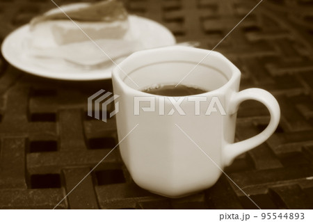カフェのテーブルの上にあるスイーツとコーヒーの入った白いカップ 95544893
