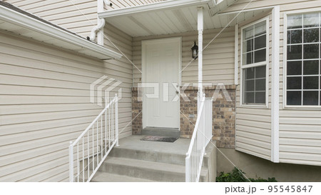 Panorama Entrance of a house with white vinyl wood siding and bay windows Panorama Entrance of a house with white vinyl wood siding and bay windows 95545847
