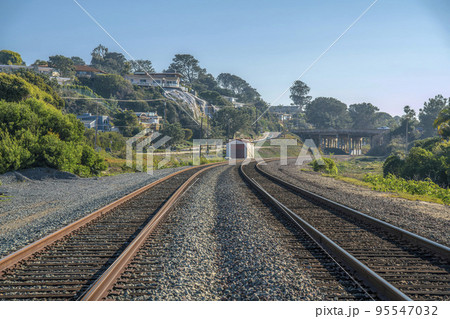 Close up of a railroad with rusty tracks along cliff homes against blue sky 95547032