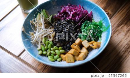 Delicious colorful vegan poke bowl with vegetables and quinoa at cafe or restaurant. Healthy lifestyle and natural organic vegetarian food concept Delicious colorful vegan poke bowl with vegetables and quinoa at cafe or restaurant. Healthy lifestyle and natural organic vegetarian food concept 95547266