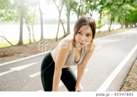 Asian woman wearing sportswear and tired engaged in fitness in public park Asian woman wearing sportswear and tired engaged in fitness in public park 95547895