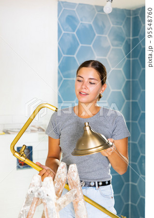 Young woman holds a shower head in the bathroom 95548760