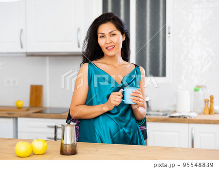Portrait of positive woman in nightdress with mug of coffee Portrait of positive woman in nightdress with mug of coffee 95548839