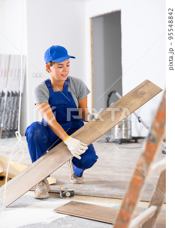 Young female builder puts laminate flooring Young female builder puts laminate flooring 95548842