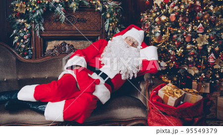 Santa Claus is sleeping in decorated room near...の写真素材