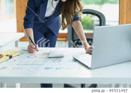 Portrait of a thoughtful Asian businesswoman looking at financial statements and making marketing plans using a computer on her desk. Portrait of a thoughtful Asian businesswoman looking at financial statements and making marketing plans using a computer on her desk. 95551497