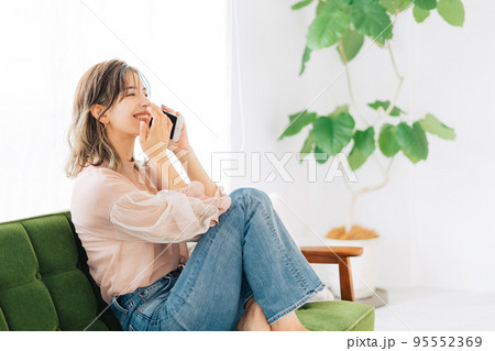 ソファーに座って電話をする若い女性 95552369
