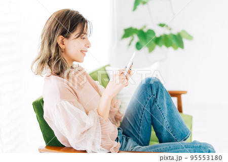 ソファーに座ってスマホを見る若い女性 ソファーに座ってスマホを見る若い女性 95553180