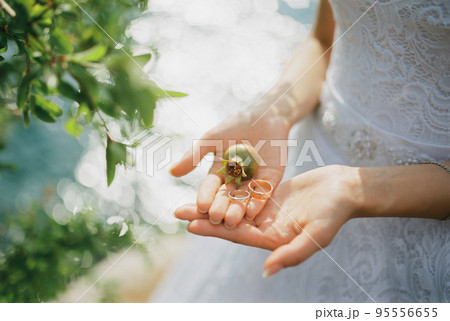 Wedding rings with a small pomegranate lie on the palms of the bride 95556655