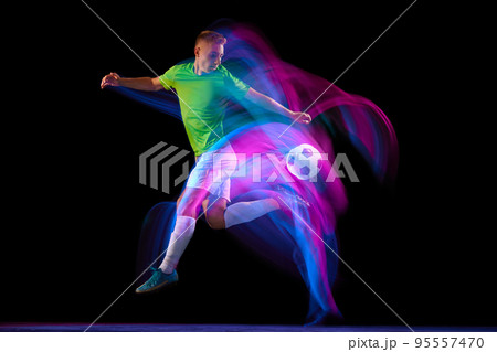 Dribbling. Young soccer, football player in motion and action with ball isolated on dark background in neon mixed light. Concept of achievement, creativity, sport, energy, championship 95557470