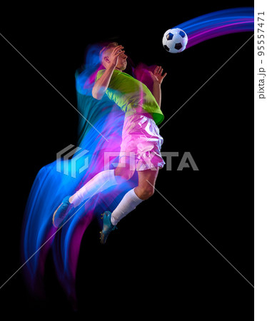 Goal. Young soccer, football player in motion and action with ball isolated on dark background in neon light. Concept of achievement, creativity, sport, energy, championship 95557471