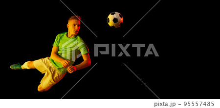 Goal. Young soccer, football player in motion and action with ball isolated on dark background in neon light. Concept of achievement, creativity, sport, energy, championship 95557485