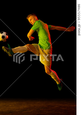 Young professional male football soccer player in motion isolated on dark background in neon light. Concept of sport, goals, competition, league, ad. Young professional male football soccer player in motion isolated on dark background in neon light. Concept of sport, goals, competition, league, ad. 95557486