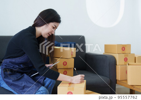 Startup small business entrepreneur of freelance Asian woman smiling and using tablet computer with Cheerful success of item online marketing packaging box and delivery SME idea concept. 95557762