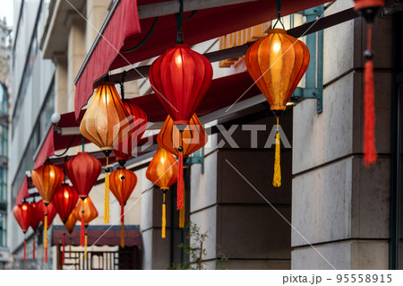 Red chinese lanterns hanging outdoors as a garland. Traditional asian light decorative lanterns for restaurants, cafe or homes. Symbols of wealth, fame, and prosperity. Red chinese lanterns hanging outdoors as a garland. Traditional asian light decorative lanterns for restaurants, cafe or homes. Symbols of wealth, fame, and prosperity. 95558915