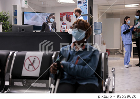 African american woman on crutches waiting to be seen in medical tower. Asian female doctor showing results to patient. Healthcare professional reviewing emergencies with curly haired receptionist. African american woman on crutches waiting to be seen in medical tower. Asian female doctor showing results to patient. Healthcare professional reviewing emergencies with curly haired receptionist. 95559620