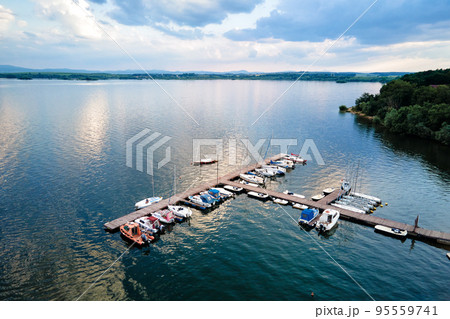 Aerial top view of boats and small jachts near wooden pier at the lake. Summer entertainment at water for tourists Aerial top view of boats and small jachts near wooden pier at the lake. Summer entertainment at water for tourists 95559741