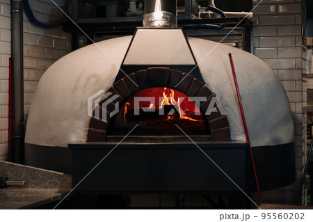 Traditional firewood oven with burning fire ready to cook traditional Italian pizza, bread or bakeries 95560202