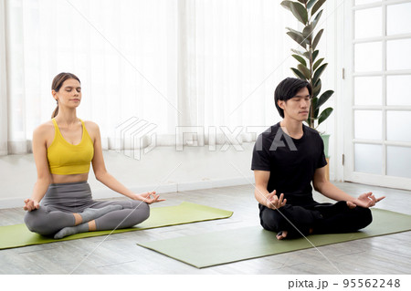 Man and woman practicing yoga and meditating for relaxation and balance life on mat in the room. Man and woman practicing yoga and meditating for relaxation and balance life on mat in the room. 95562248