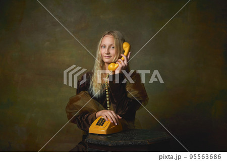 Ring. Elegant young girl with long blonde hair wearing medieval dress like Mona Lisa replica over dark vintage background. Vintage style, art, fashion, comparison of eras concept. 95563686
