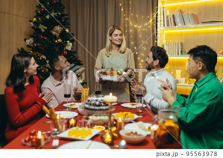 Festive Christmas New Year dinner, various friends celebrate new year together at home, have dinner and drink alcohol at the festive table. Festive Christmas New Year dinner, various friends celebrate new year together at home, have dinner and drink alcohol at the festive table. 95563978