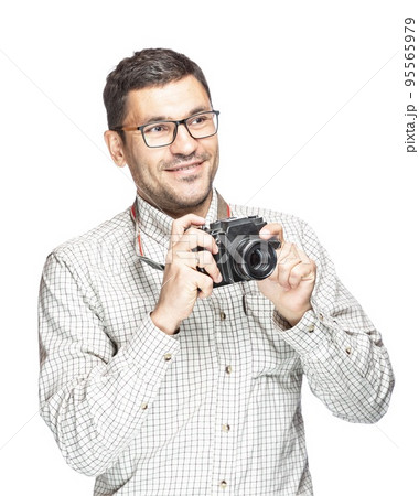 Handsome man in glasses and a plaid shirt, smiling and taking pictures with an vintage camera Handsome man in glasses and a plaid shirt, smiling and taking pictures with an vintage camera 95565979