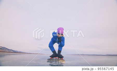 The child train on ice speed skating. The athlete at the start, in a sports stance. The kid girl skates in the winter in sportswear, sport glasses. The child train on ice speed skating. The athlete at the start, in a sports stance. The kid girl skates in the winter in sportswear, sport glasses. 95567145