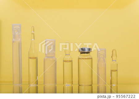 Glass medical ampoule vial for injection. Medicine is liquid sodium chloride with of aqueous solution in ampulla. Close up. Bottles ampule multicolor. Glass medical ampoule vial for injection. Medicine is liquid sodium chloride with of aqueous solution in ampulla. Close up. Bottles ampule multicolor. 95567222