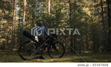 The woman travel on mixed terrain cycle touring with bike bikepacking. The traveler journey with bicycle bags. Magic forest park. The woman travel on mixed terrain cycle touring with bike bikepacking. The traveler journey with bicycle bags. Magic forest park. 95567608