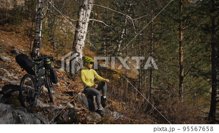 The woman travel on mixed terrain cycle touring with bikepacking. The traveler journey with bicycle bags. Sport tourism bikepacking. 95567658